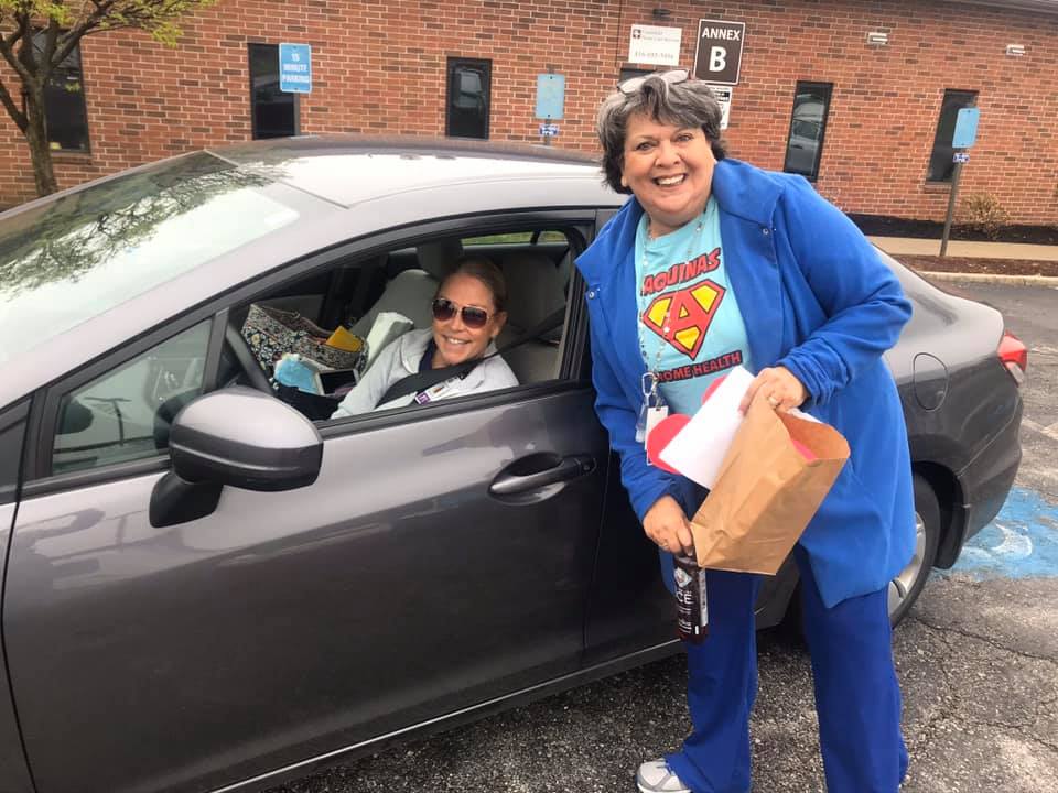 Photo of a woman posing next to a woman smiling driving a car.