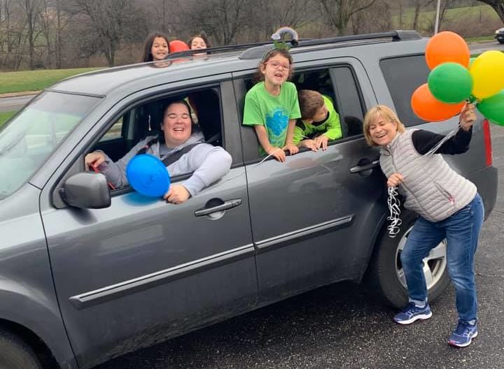 Photo of women and children smiling in a car with balloons.