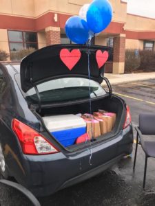 Photo of a car trunk with gifts, balloons, and heart cutouts in it.